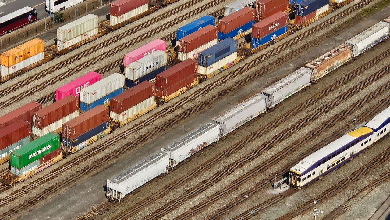 cta-02 Aerial shot showcasing colorful freight containers on train tracks in a busy transportation yard.