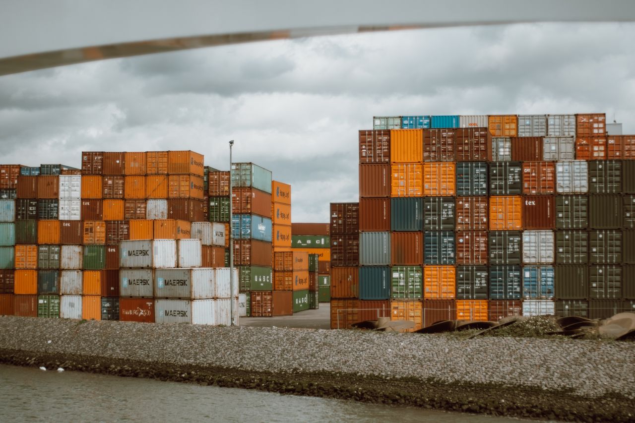 portfolio-01 Colorful shipping containers stacked in Rotterdam harbor, under overcast skies.