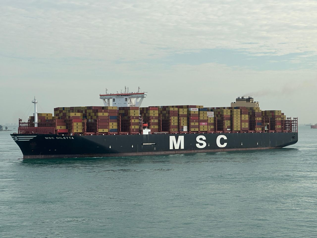 MSC cargo ship with stacked containers navigating open waters under cloudy sky.