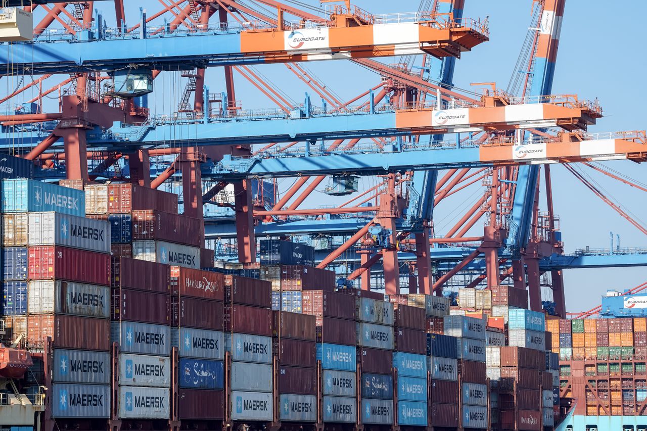 gallery-03 A bustling view of the Hamburg port showing cranes and stacked shipping containers.